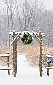 Rustic fence and arbor with holiday wreath near prairie in winter, Marion County, Illinois