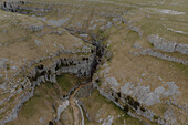 Aerial view stream through rugged cliffs in remote landscape, Mildale, North Yorkshire, England