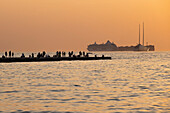Blick auf die Menschen auf der Mole bei Sonnenuntergang im Hafen von Triest, Friaul-Julisch-Venetien, Oberitalien, Italien, Europa