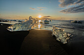 Europa, Island. Morgenlicht scheint auf Eisbrocken am Diamond Beach in der Nähe der Gletscherlagune Jokulsarlon an der Südküste.