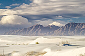 USA, New Mexico, White Sands National Monument. Clouds over mountains and sand