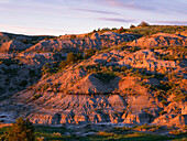 USA, North Dakota, Theodore Roosevelt National Park, Sunset light defines eroded sedimentary hillside near Boicourt Overlook in the South Unit.