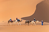 Afrika, Marokko. Touristen reiten auf Kamelen in Erg Chebbi in der Wüste Sahara.