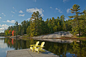 Kanada, Ontario, Grundy Lake Provincial Park. Muskoka-Stühle auf einem Steg am See.