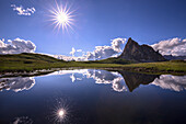 Italy, Dolomites, Giau Pass. Sun reflection in mountain tarn.