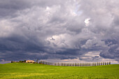 Italien, Toskana, Val d'Orcia. Bauernhaus und Gewitterwolken bei Sonnenuntergang.