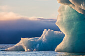 Norwegen, Svalbard, Kvitoya. Eisberg und Nebelbank bei Sonnenaufgang.