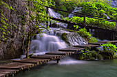 Kroatien, Nationalpark Plitvicer Seen. Ein Wasserfall und ein Holzsteg.