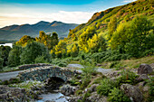 Ashness Bridge and the last rays of sunlight on the mountains above Derwentwater, the Lake District, Cumbria, England