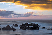 USA, Hawaii, Big Island of Hawaii. Laupahoehoe Point Beach Park, Sunrise over waves and rough volcanic rock.