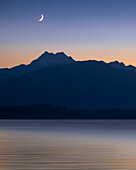 USA, Washington State, Seabeck. Crescent moon at sunset over Hood Canal and Olympic Mountains.