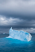 Antarktis, Insel Südgeorgien. Einsamer Eisberg und stürmischer Sonnenuntergang