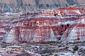 USA, Utah, Wayne County. Farbenfrohe Bentonitschichten in der Nähe und entfernte Schieferablagerungen von North Caineville Mesa in der Abenddämmerung.