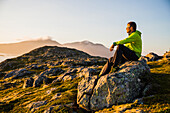 Norwegen, Lofoten, Mann im Sonnenuntergang über dem Fjord