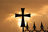 A wrought-iron cross on a fence in Syria at sunrise.