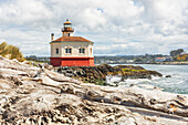 Bandon, Oregon, USA. Strandstämme und der Coquille River Lighthouse an der Küste von Oregon.