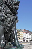 Lion at the base of the Max-Josef monument on Max-Josef-Platz with houses on Residenzstrasse