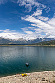 Lonely boat moored in the lake of Santa Croce surrounded by the Belluno Dolomites, Alpago, Belluno, Veneto, Italy