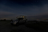Einzelnes Beleuchtetes Wohnmobil steht nachts am Meer. Klintehamn, Gotland, Schweden.