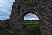 View through the archway of Saint Brita's chapel to the Kappelluddens lighthouse. Light dawn. Oland, Sweden.