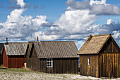 Kleine Fischerhütten stehen eng aneinander. Schäfchenwolken. Farö, Gotland, Schweden.