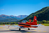 Propellerflugzeug am Flughafen mit Blick auf die Berge an einem sonnigen Tag mit blauem Himmel in Lugano, Tessin, Schweiz.