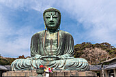Der große Buddha, Daibutsu, Opfergaben vorne, blauer Himmel oben in Kamakura, Japan