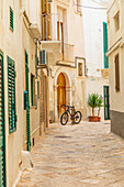 Italien, Apulien, Metropole Bari, Monopoli. Schmale Straße zwischen Gebäuden, mit einem Fahrrad.