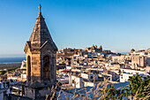 Italy, Apulia, Province of Brindisi, Ostuni. View over the town with unidentified church bell tower in foreground and Church of San Vito Martire on hill in background.