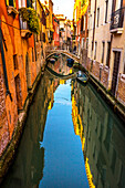 Ein farbenfroher kleiner Kanal und eine Brücke schaffen eine schöne Reflexion in Venedig, Italien.