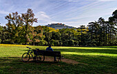 Cyclists during a break on a bench in Parco Termale overlooking Montecatini Alto, Montecatini Terme, Tuscany, Italy