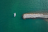 Top view of a sailing boat leaving the port of Sistiana on the Gulf of Trieste in Trieste, Friuli Venezia Giulia, Italy.