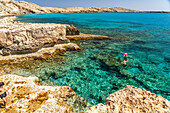 Tourists bathe in the crystal clear turquoise waters of Cape Greco Peninsula, Agia Napa, Cyprus, Europe