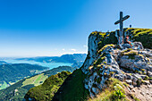 Gipfelkreuz und Felswand am Schafberg mit Blick auf den Attersee und das Höllengebirge, Salzkammergut, Österreich