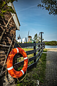 Rettungsring am Zaun mit Windmühlen im Hintergrund, Niederlande