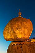 Kyaiktiyo-Pagode (Goldfelsen) bei Sonnenuntergang, eine kleine Pagode, die auf der Spitze eines Granitfelsens gebaut wurde, der mit goldenen Blättern bedeckt ist, die von Anhängern aufgeklebt wurden, Mon-Staat, Myanmar