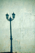 Morning shadow of a lamppost on light blue-green house wall in Trinidad, Cuba.