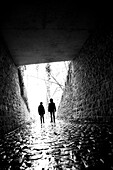 Two children standing at the end of a tunnel