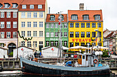 Old fishing cutter in front of the historic houses in Nyhavn, Copenhagen, Denmark
