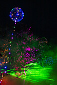 Colorful laser show with balloons and illuminated trees