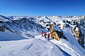 Three people on ski tour looking at Zillertal Alps, Höllensteinkar, Tux Valley, Zillertal Alps, Tyrol, Austria