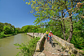 Two people ride bikes across bridge on Canal du Midi, Pont-Canal de l'Argent Double, Canal du Midi, UNESCO World Heritage Canal du Midi, Occitania, France