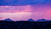 Usa, New Mexico, Lamy, Monsoon storm clouds forming over desert landscape at dusk