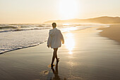 Teenage girl (16-17) walking on Grotto Beach at sunset