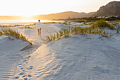 South Africa, Hermanus, Teenage girl (16-17) walking on sand dunes on Grotto Beach