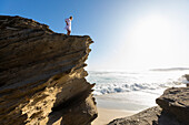 Teenager-Mädchen (16-17) steht auf einer Klippe mit Blick aufs Meer, Hermanus, Südafrika