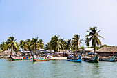 Fischerdorf Ada Foah mit strohgedeckten Hütten und bunt bemalten Booten am Ufer des Volta-Flusses in der Region Greater Accra im Osten von Ghana in Westafrika