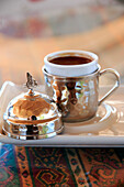 Turkey, Central Anatolia, Nevsehir Province, Uchisar café scene, Turkish coffee being served in cup with Sultan Suleyman's monogram.