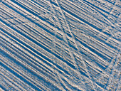 Schneelandschaft mit Muster aus Reifenspuren im Acker im Sempttal bei Wifling in Oberbayern, Bayern, Deutschland