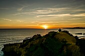 Wanderer auf dem Kliff beobachtet den Sonnenuntergang über dem Meer bei Albufeira, Algarve, Portugal